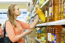 Young woman buys sunflower oil in supermarket