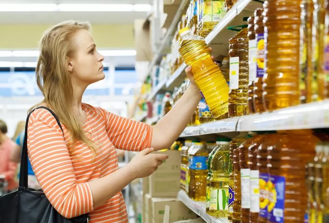 Young woman buys sunflower oil in supermarket
