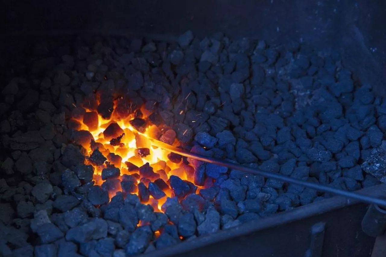 A glowing metal rod in the hot coals in a blacksmith‘s forge.