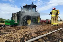 Strażacy dogaszają palący się ciągnik na polu