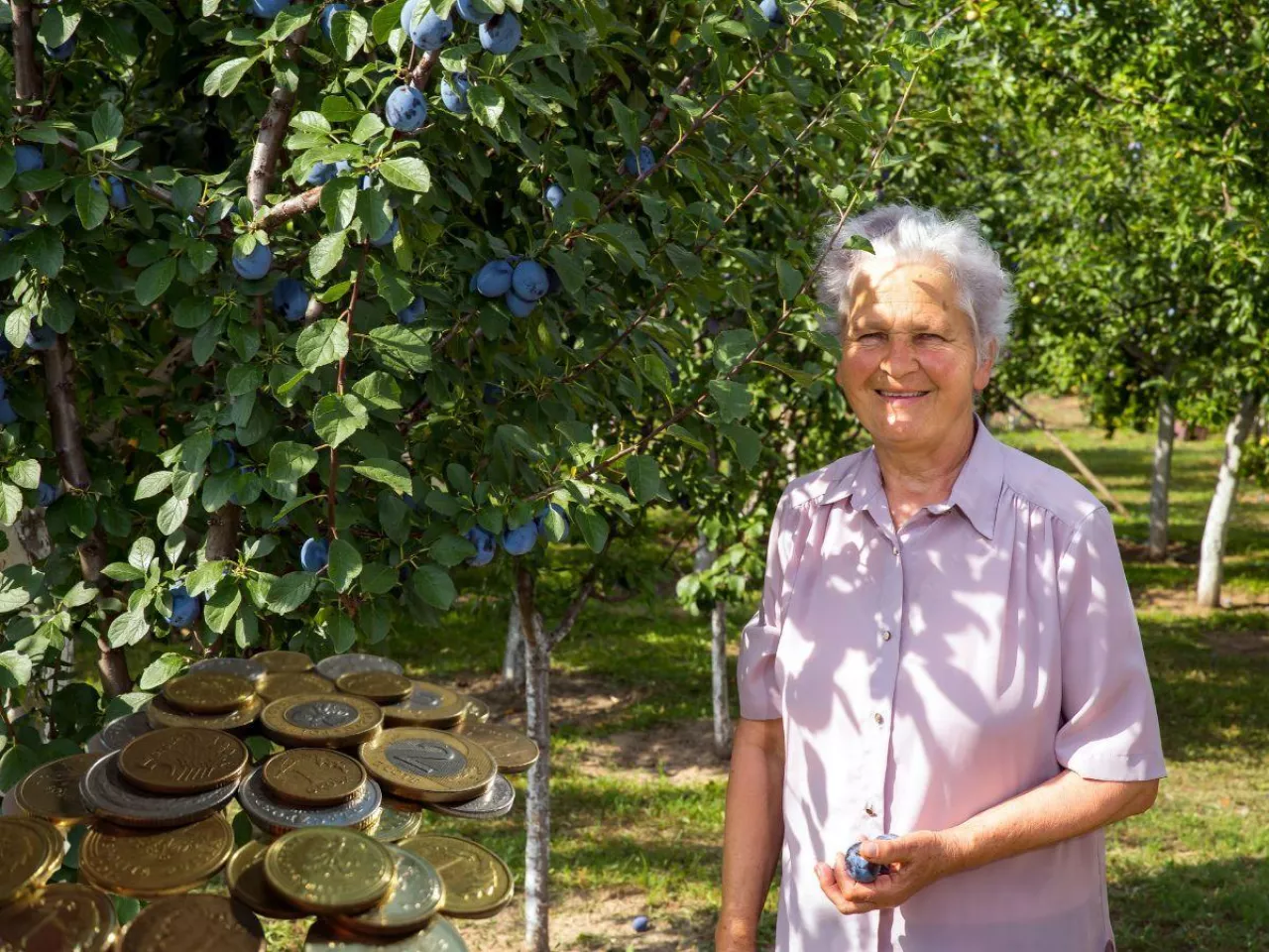Starsza uśmiechnięta kobieta wstojąća pod drzewem
