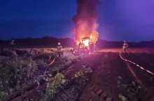 Strażacy walczą z pożarem ciągnika rolniczego na polu