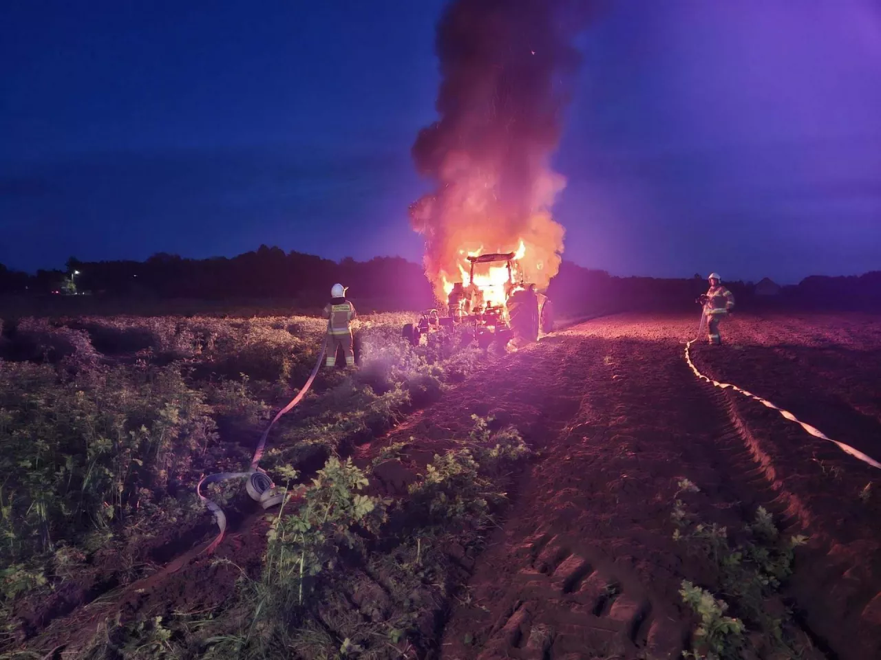 Strażacy walczą z pożarem ciągnika rolniczego na polu