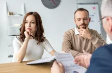 selective focus of pensive man and thoughtful woman sitting near car dealer in office