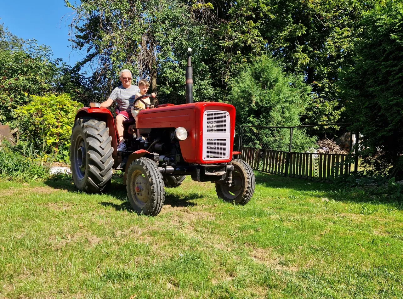 wnuk z dziadkiem na ciągniku rolniczym