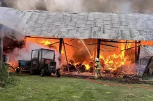 Strażak próbujący ugasić palące się budynki gospodarcze