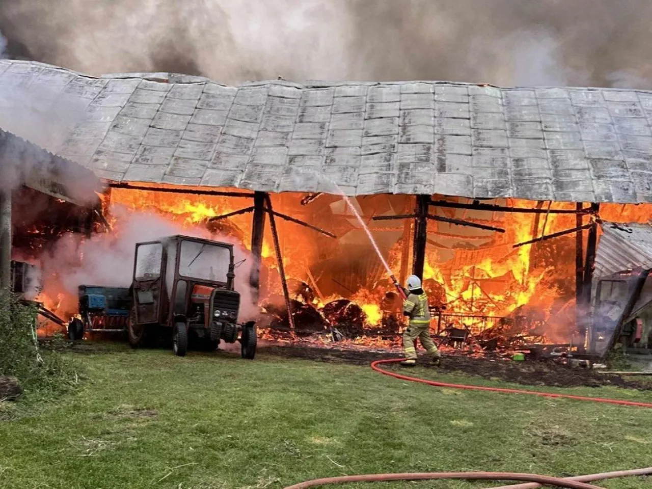 Strażak próbujący ugasić palące się budynki gospodarcze