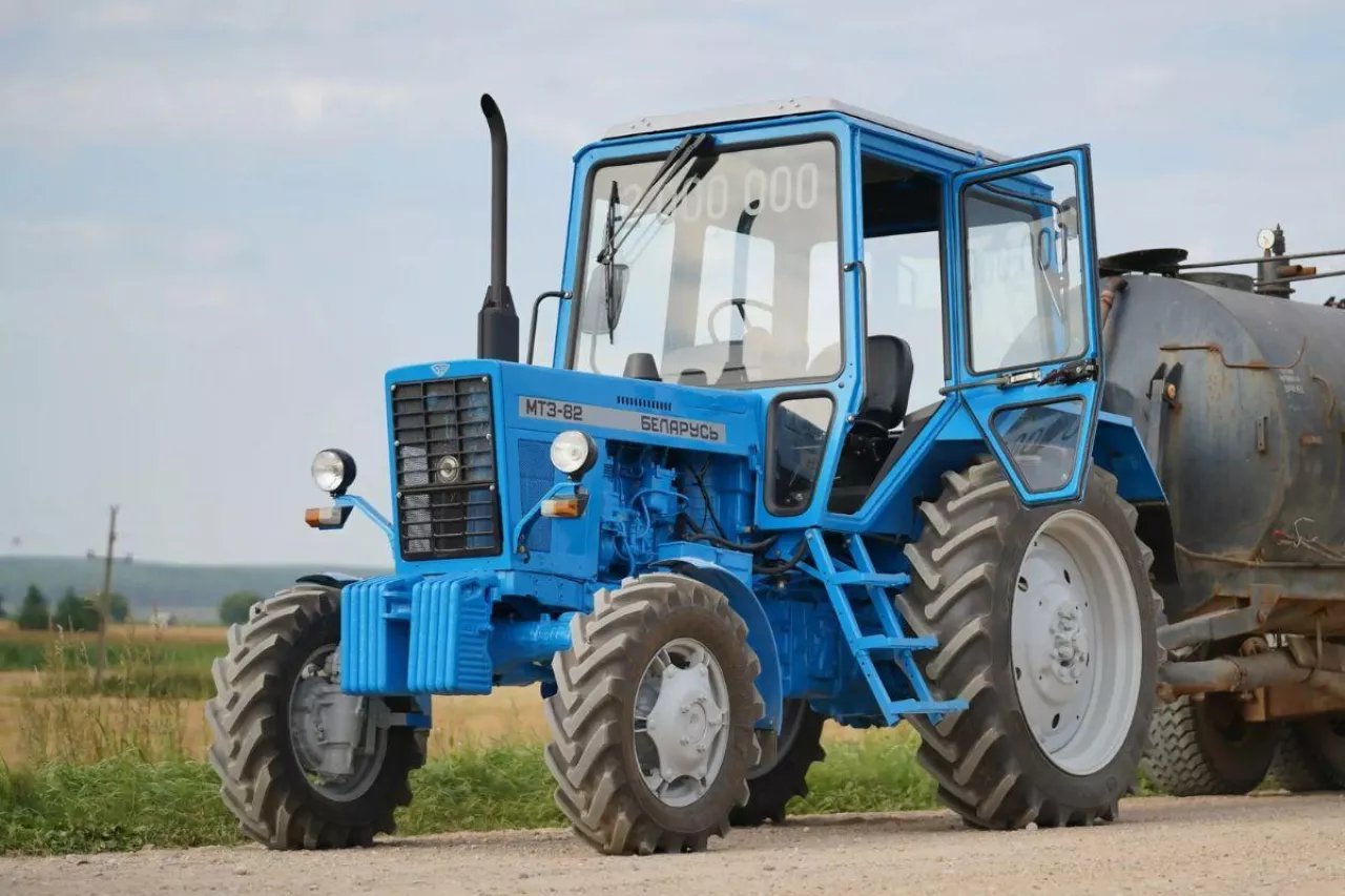 Niebieski ciągnik Belarus MTZ-82 na polnej drodze.