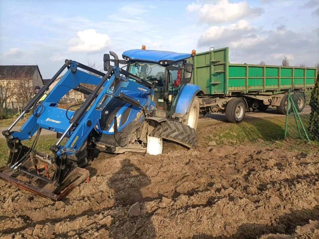 Rozbity ciągnik rolnicy New Holland z przyczepą w rowie