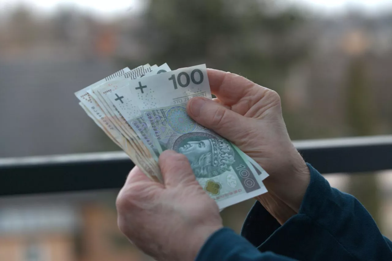 dłonie trzymające polskie banknoty stuzłotowe