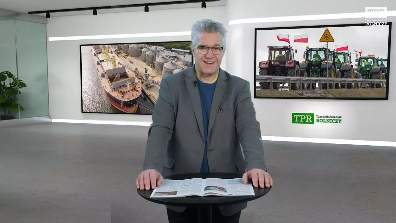 Mężczyzna w szarej marynarce przed mównicą z rozłozoną gazetą