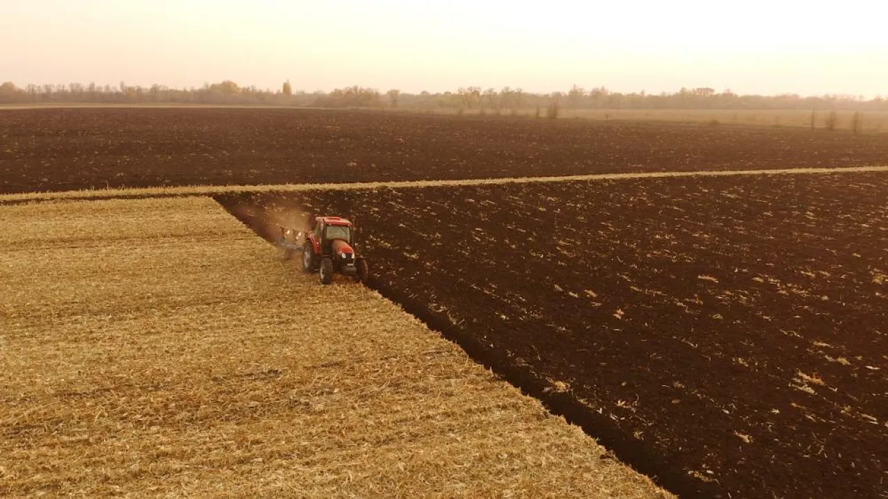 Tractor working on farm field in autumn time. Plowing ground before sowing. Agronomy, farming concept.