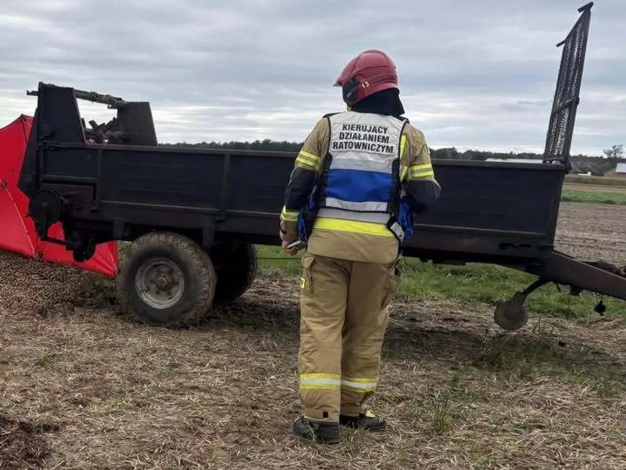 Strażak w ubraniu specjalnym stojący przed rozrzutnikiem obornika
