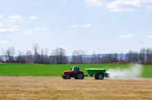 Ciągnik z rozsiewaczem nawozu podczas pracy na polu