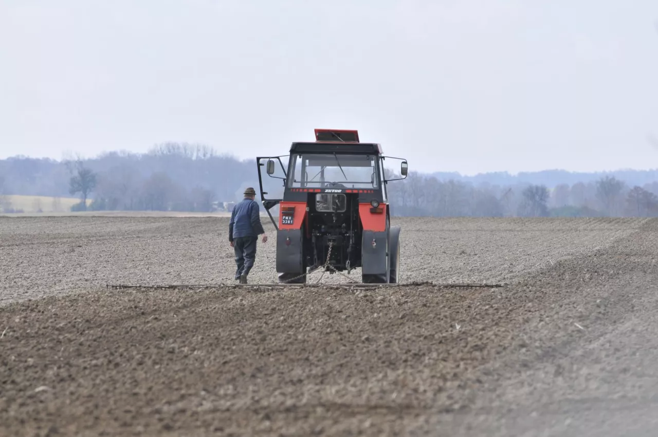 traktor i rolnika stojący obok, na polu