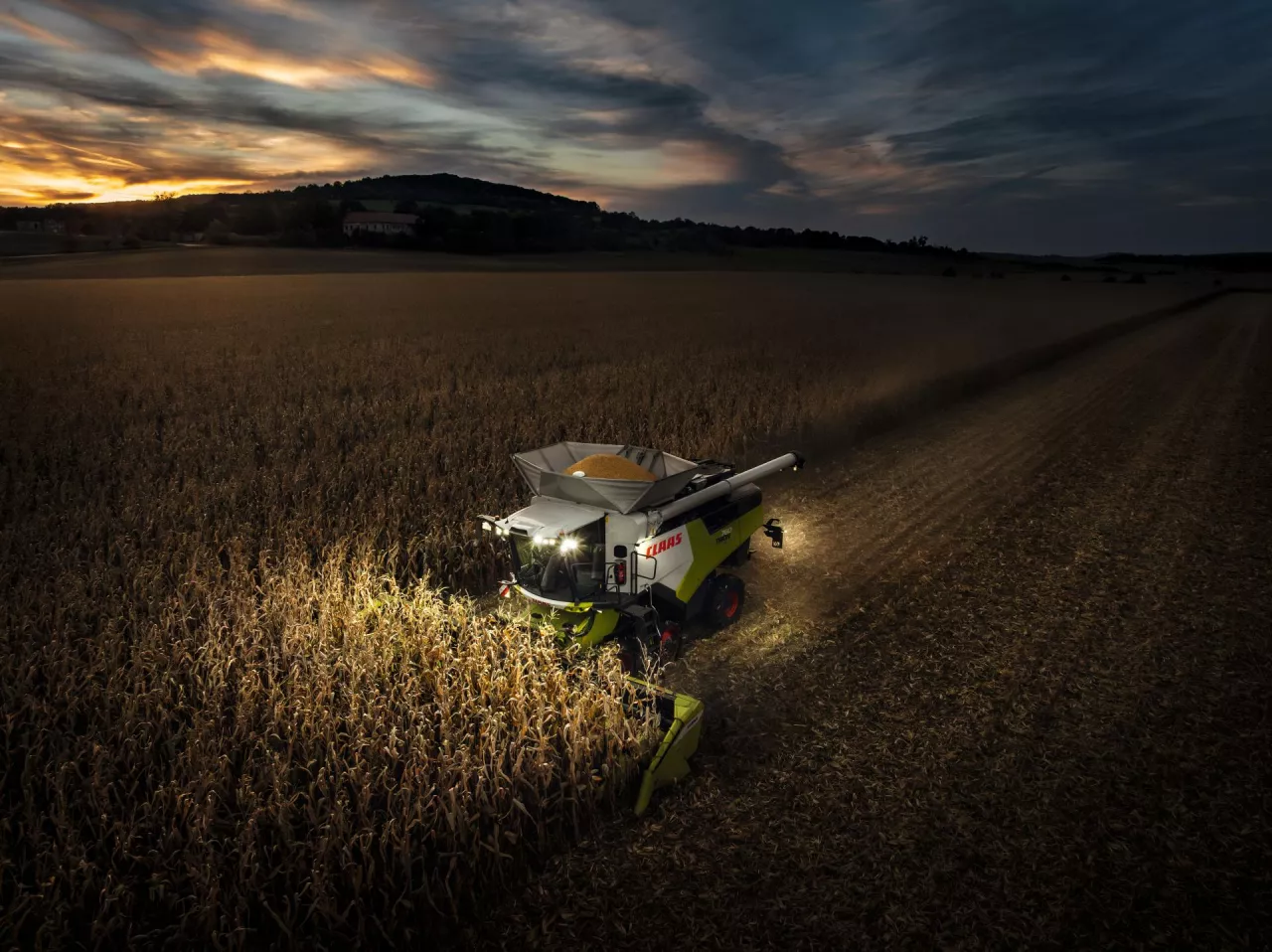 Oświetlony podczas nocnych żniw kombajn Claas Trion 760