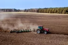 Ciągnik rolniczy pracuje na polu podczas wiosennej uprawy gleby