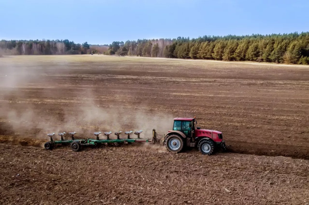 Ciągnik rolniczy pracuje na polu podczas wiosennej uprawy gleby