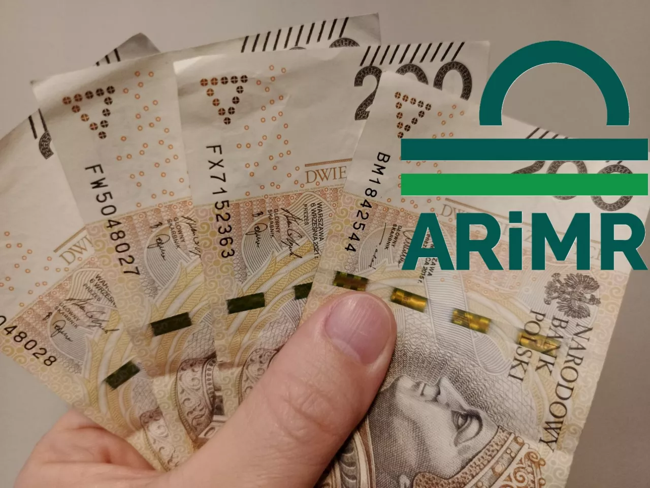 dłoń trzymająca banknoty, logo ARiMR po prawej