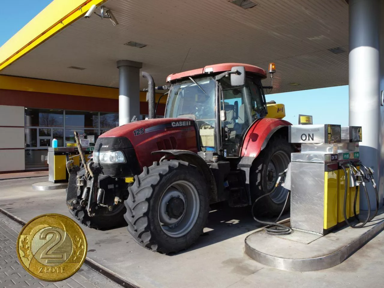 traktor tankujący na stacji paliw, po lewej na dole moneta 2 złote