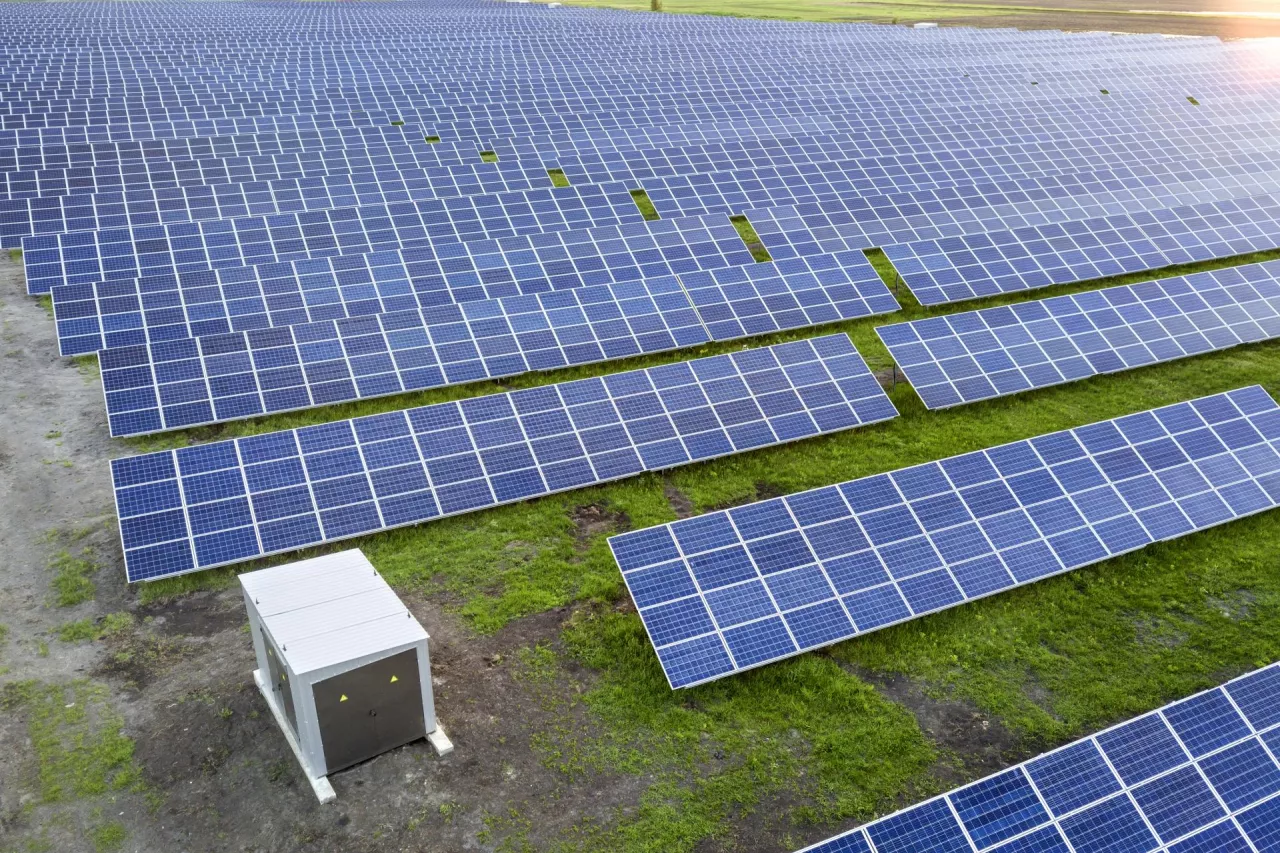 Large field of solar photo voltaic panels system producing renewable clean energy on green grass background.